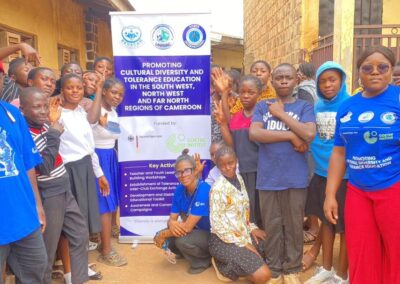 UNIMAC staff and students gathered beside a banner promoting cultural diversity and tolerance education in the South West, North West and Far North regions of Cameroon