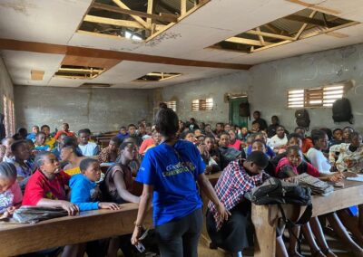 A UNIMAC staff member in a blue T-shirt speaking to a full classroom of students