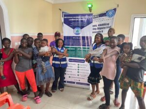 Participants gathered around the UNIMAC banner at a menstrual hygiene lecture
