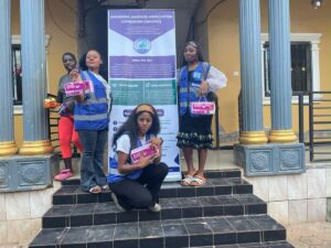 UNIMAC volunteers with sanitary kits beside the UNIMAC banner